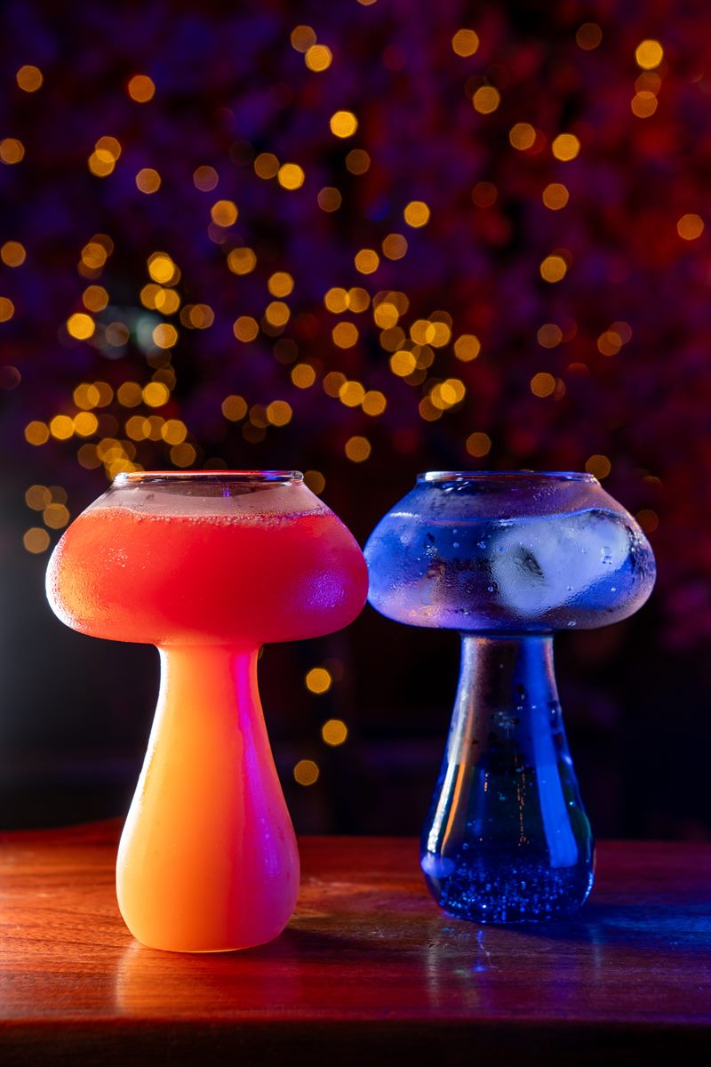 Two mushroom-shaped cocktail glasses, one orange and one blue
